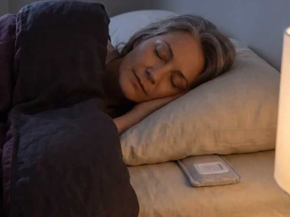 A woman in bed at night, the speaker under her pillow