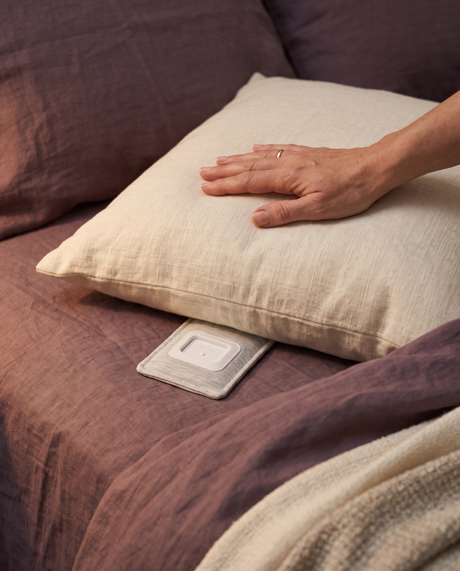A hand on the pillow with the Drowsie lying flat underneath